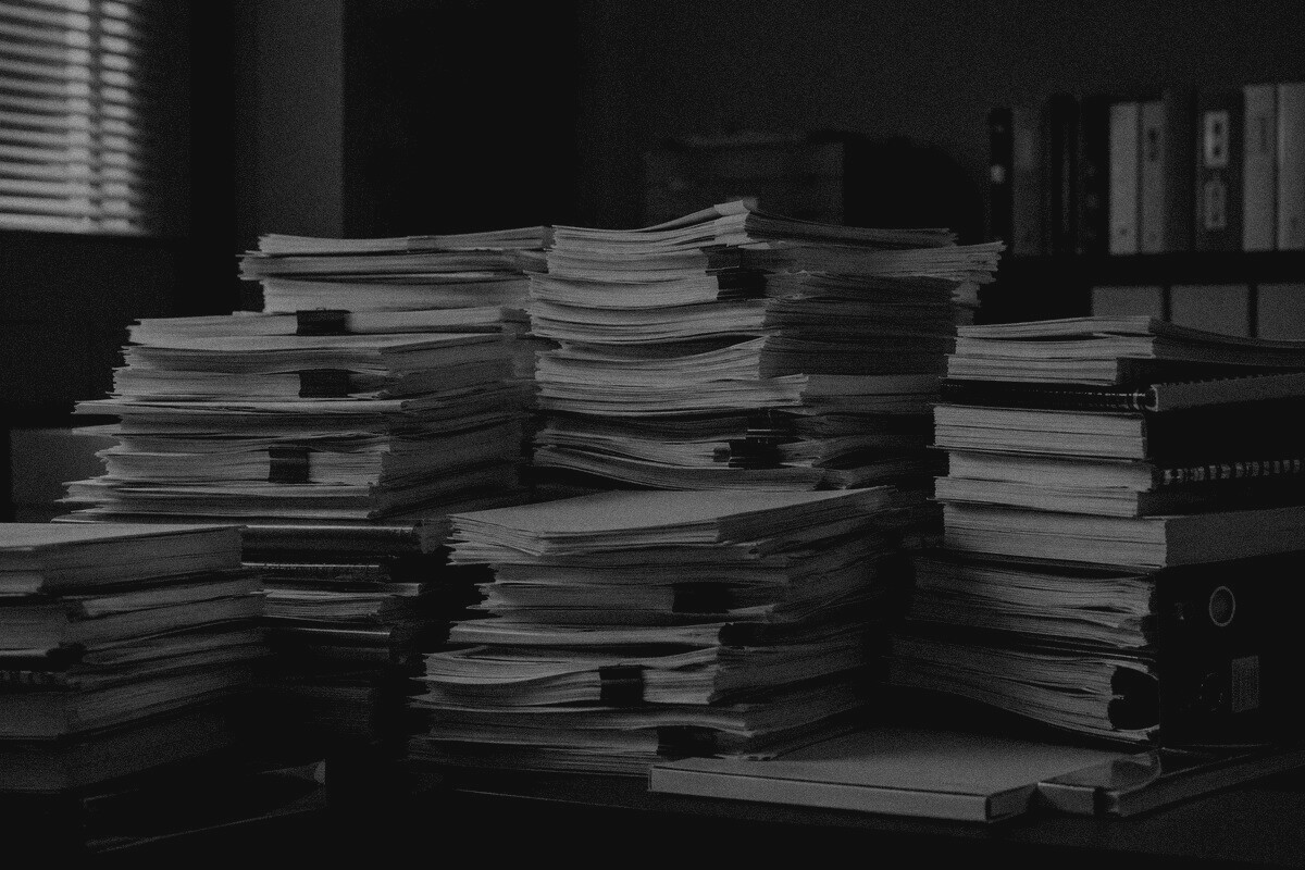 仕様書や業務資料が大量に積み重なった様子